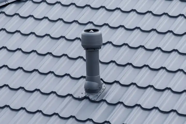 Plastic roof vent pipe on grey metal tile roofing